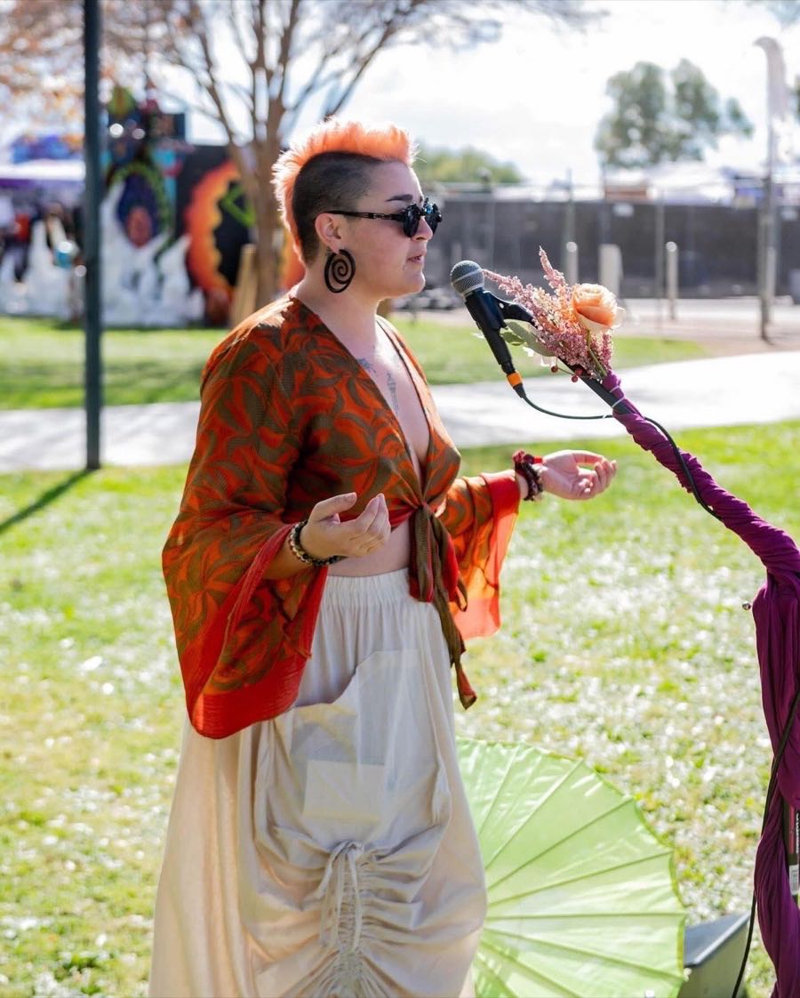 Kat McGill guiding a group Liquid Breathwork and Reiki session at Gem and Jam music festival in Arizona, attendees lying on the grass