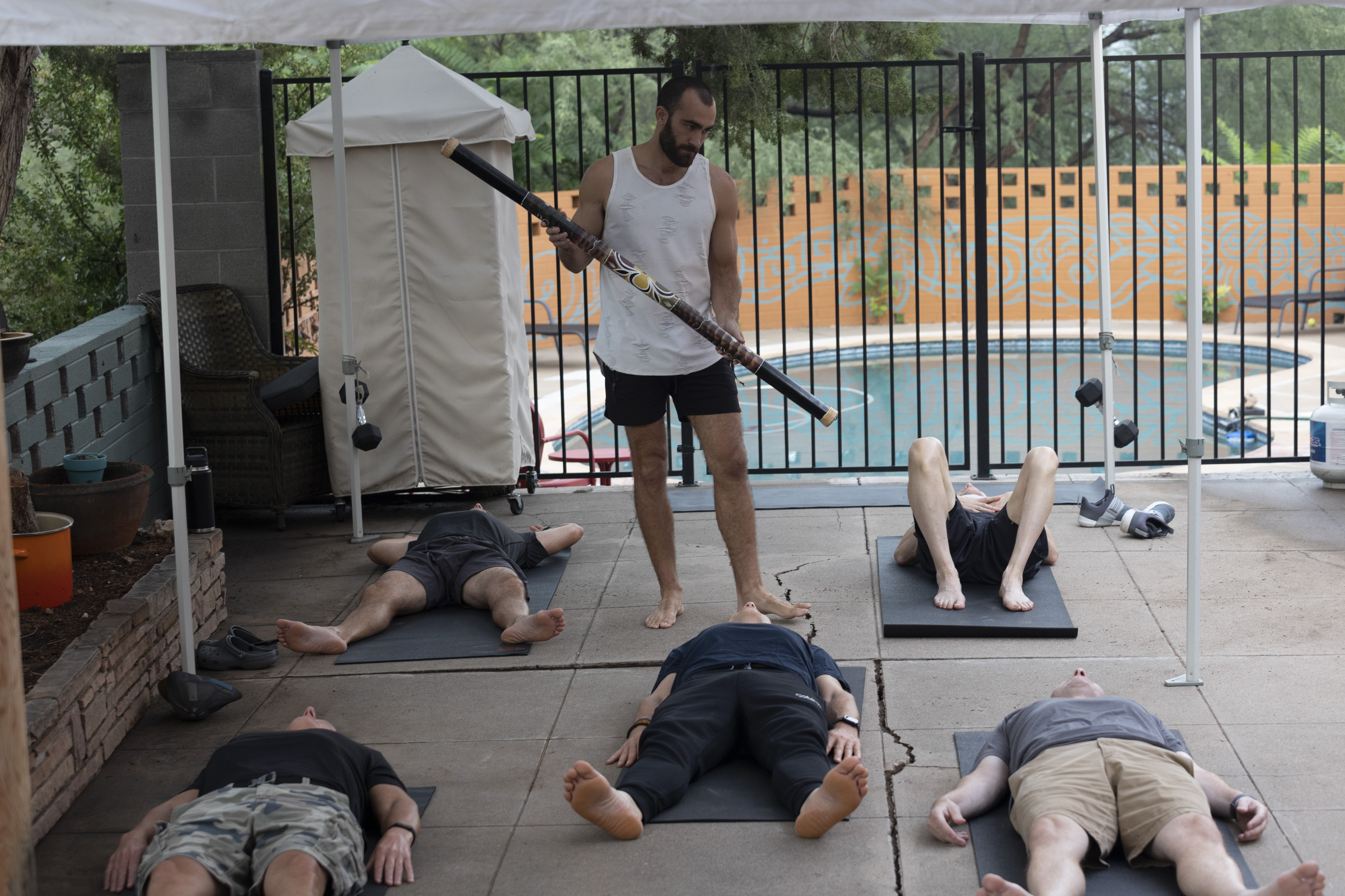 Ryan guiding breathwork with didgeridoo at retreat poolside session